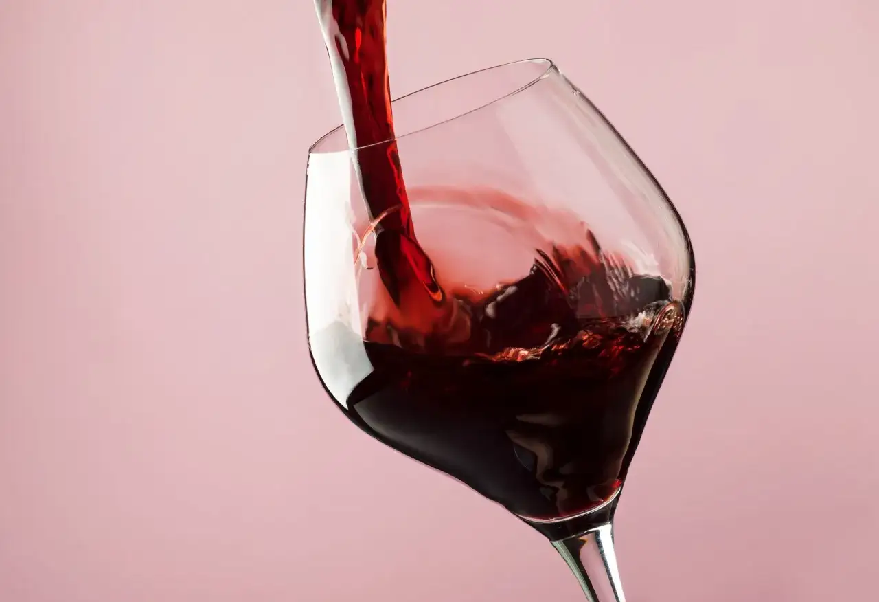 Czerwone wino nalewane do kieliszka. Czy to siarczyny i aminy biogenne powodują, że po winie boli głowa?