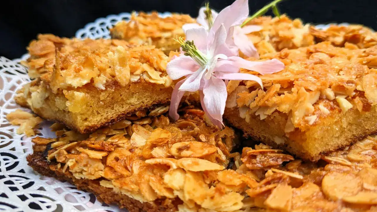Leckere Blechkuchen-St&uuml;cke mit Mandel-Topping, inspiriert von einem Tassenkuchen Rezept. Eine zarte Bl&uuml;te ziert die s&uuml;&szlig;e K&ouml;stlichkeit.