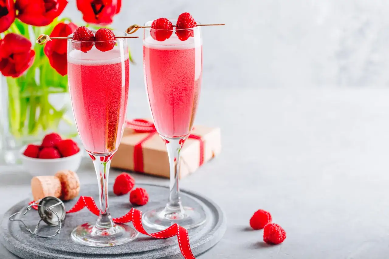 Dwa kieliszki musującego koktajlu z malinami, idealne do celebracji. Jak pić chambord likier? Właśnie tak!