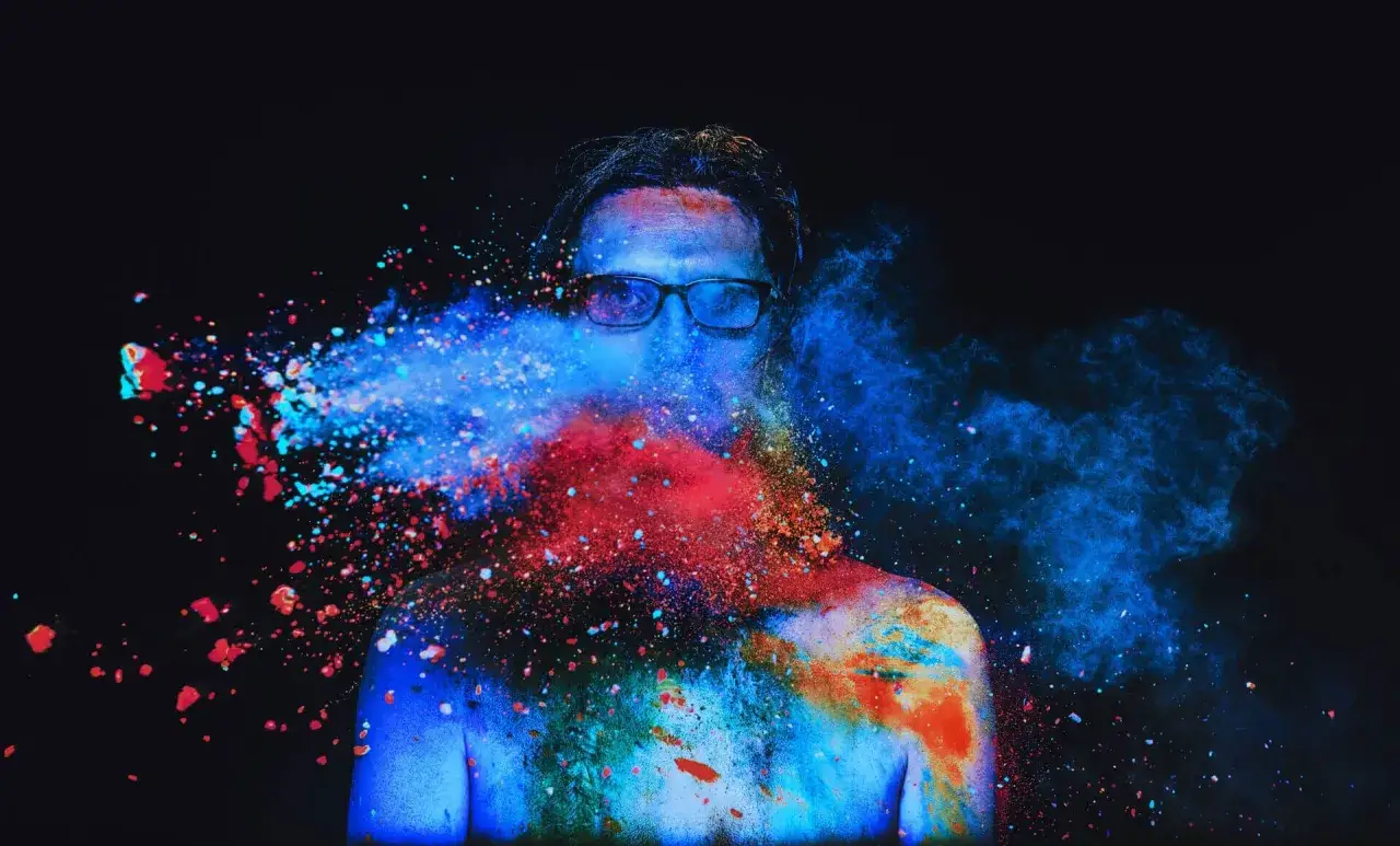 Steven Wilson to the bone, w eksplozji kolorowego proszku, niebieskiego i czerwonego, na czarnym tle.