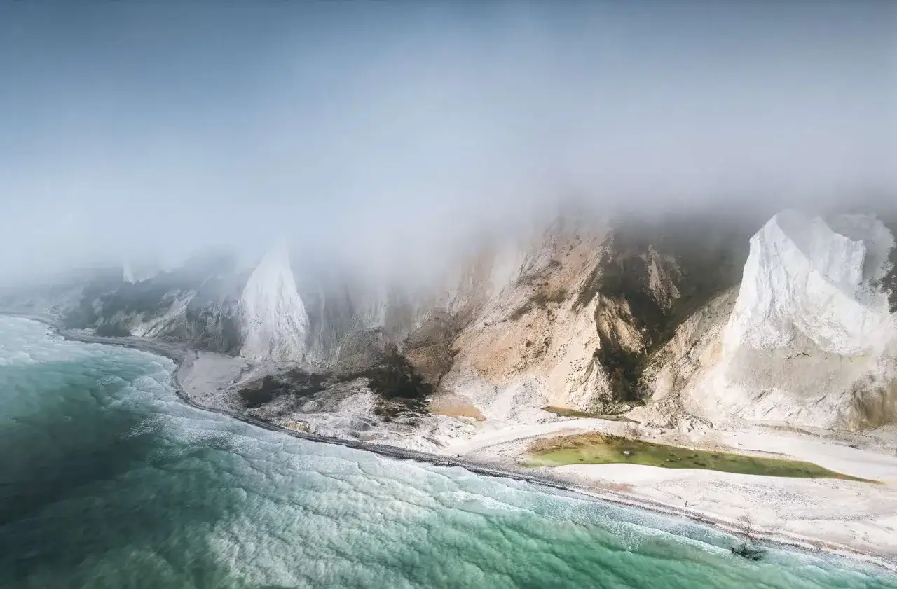 Dimma sveper in de vita klipporna i Danmark. Havet sköljer mot stranden vid de dramatiska vita klipporna.