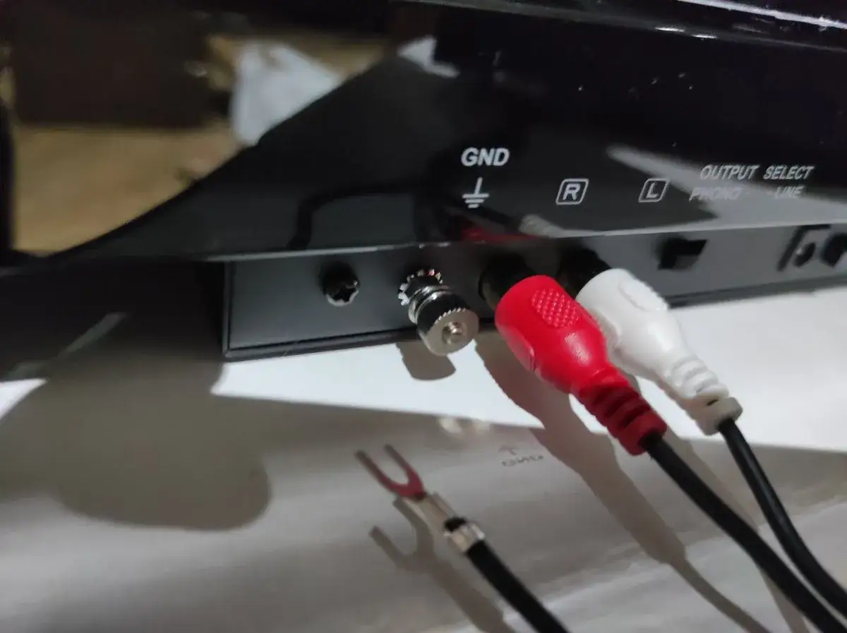 Złącze GND na gramofonie, gotowe do podłączenia przewodu uziemiającego. Czerwony i biały kabel RCA są już podłączone.
