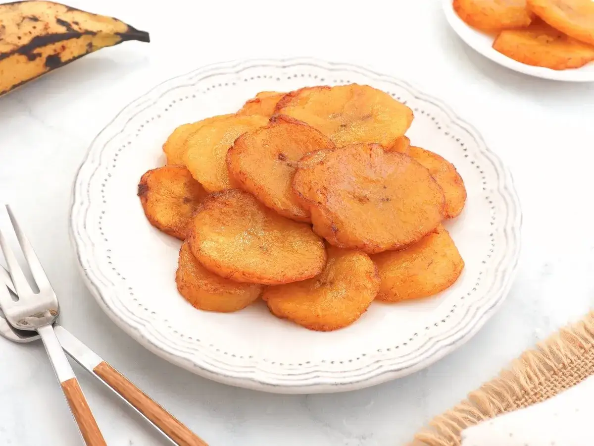 Plato con rodajas doradas de plátano frito, un bocado dulce y crujiente.