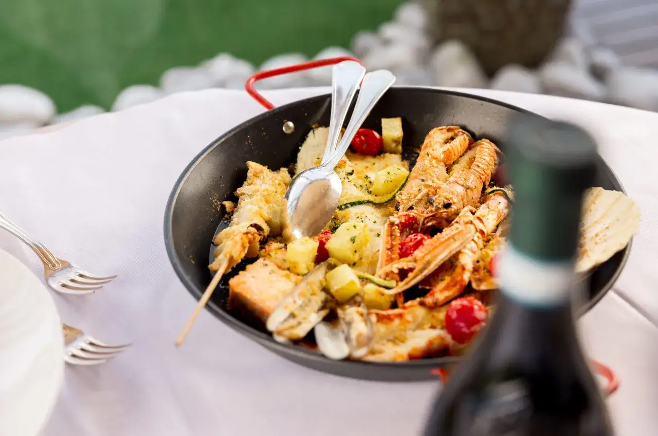 Piatto di pesce misto con scampi, patate e pomodorini, perfetto per i **lugana abbinamenti**.