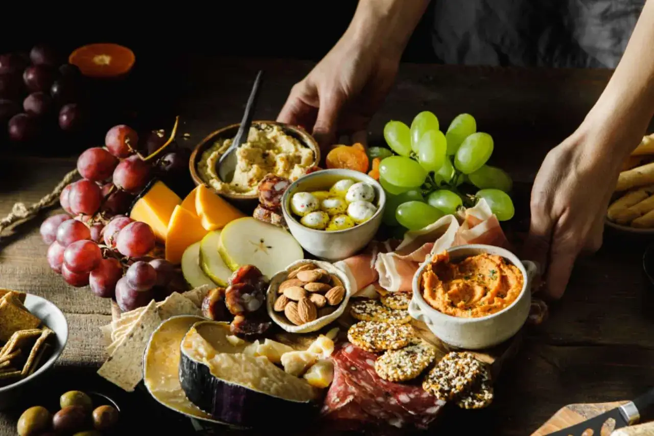 Bogata deska serów, wędlin, owoców i dipów, idealna na zdrową przekąskę w stylu dieta śródziemnomorska.