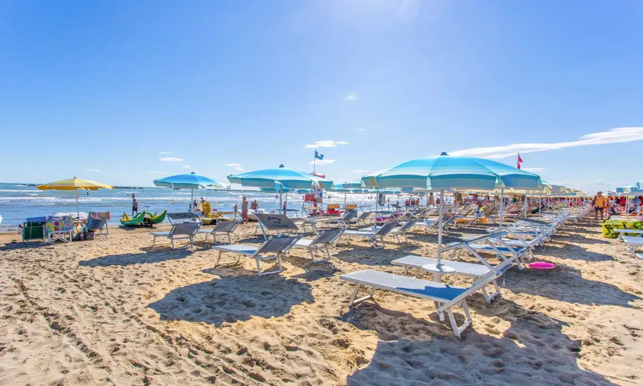 Spiaggia di Cesenatico mare, con file di lettini e ombrelloni azzurri sotto un cielo limpido.
