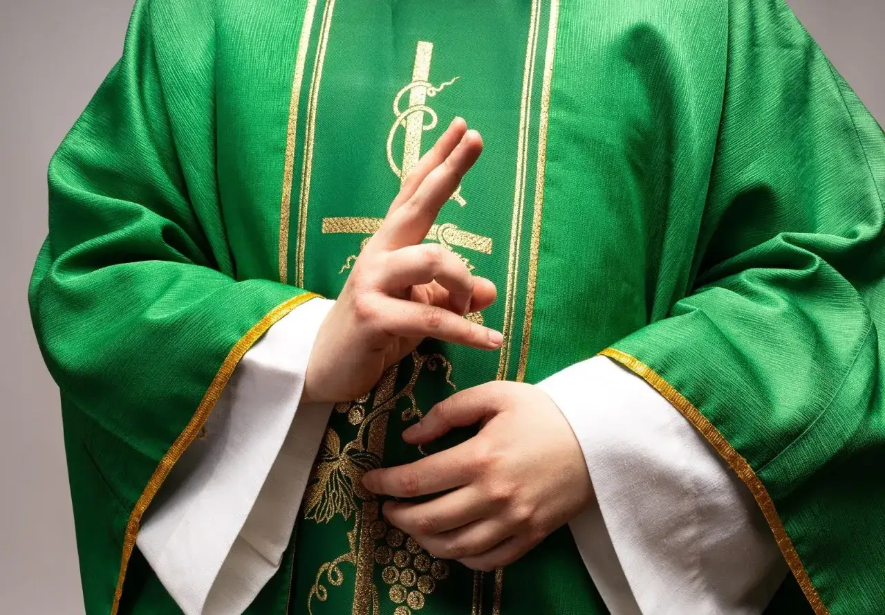 Kapłan w zielonej szacie z haftem. Dyskretne pytanie: ile bierze kościelny za pogrzeb?