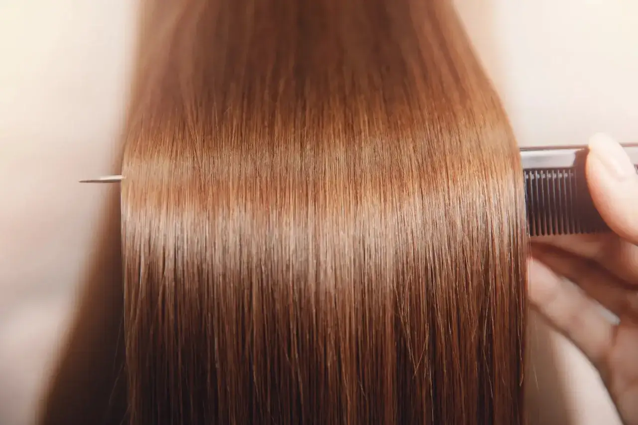 Peine negro desenredando cabello casta&ntilde;o, que luce un poco opaco.