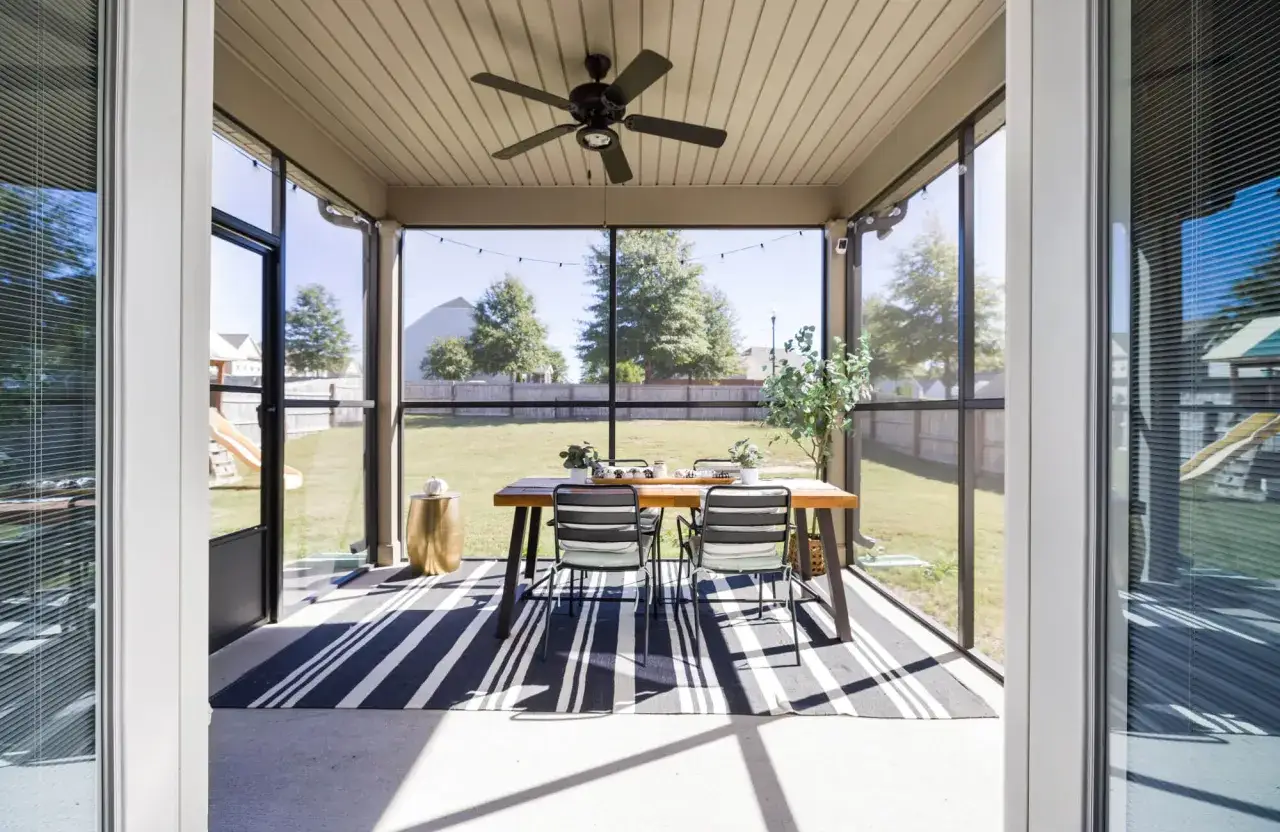 Screened porch with dining set on a striped rug. The question of do polypropylene rugs get hot in the sun is relevant here.