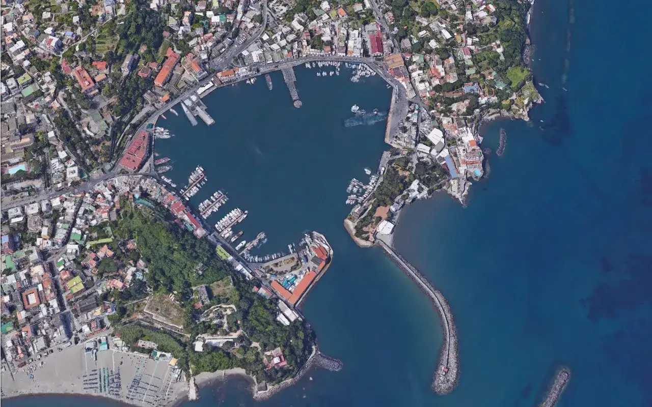Vista aerea del porto turistico di Ischia, con numerose imbarcazioni ormeggiate e la citt&agrave; che si estende verso l'entroterra.