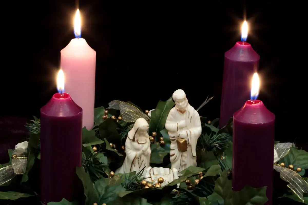 Three purple and one pink candle burn brightly, illuminating a nativity scene. This image represents the second Sunday of Advent readings.