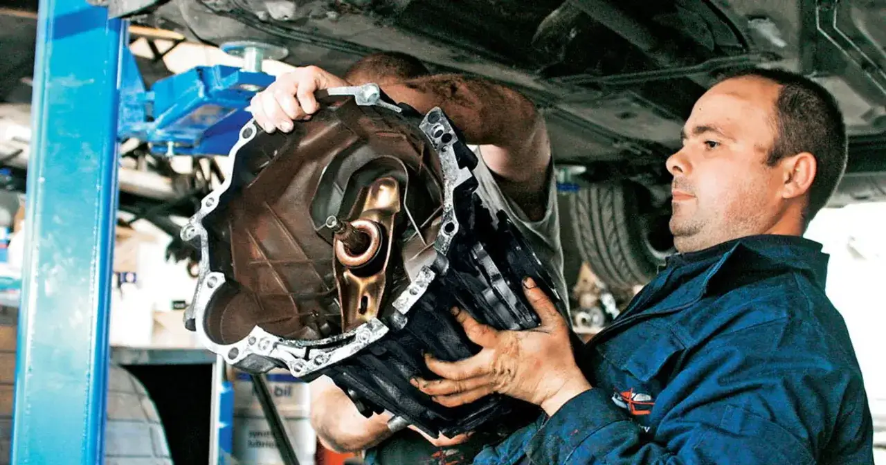 Mechanicy wyciągają skrzynię biegów, która sprawiała problemy, bo biegi wchodzą z oporem.