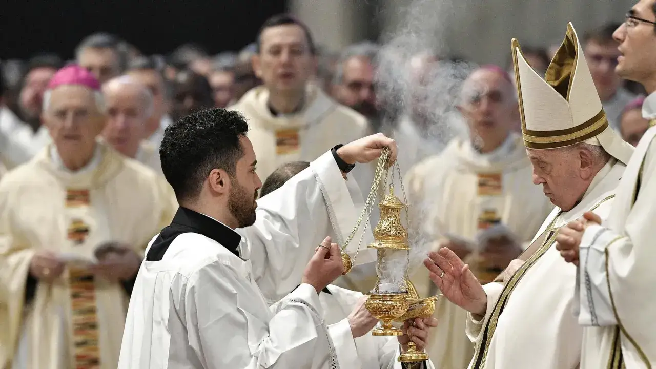 Ein Diakon hält ein goldenes Räuchergefäß, während Papst Franziskus bei einer christlichen Osterzeremonie Weihrauch segnet.