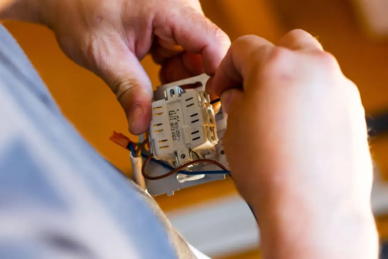 Elektryk podłącza przewody do łącznika. Sprawdź nasze usługi elektryczne cennik.