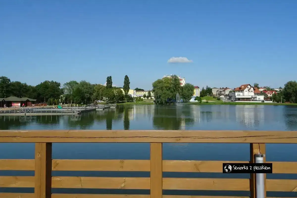Spokojne jezioro z pomostami i budynkami w tle, idealne miejsce na relaks. Suwałki atrakcje dla każdego.
