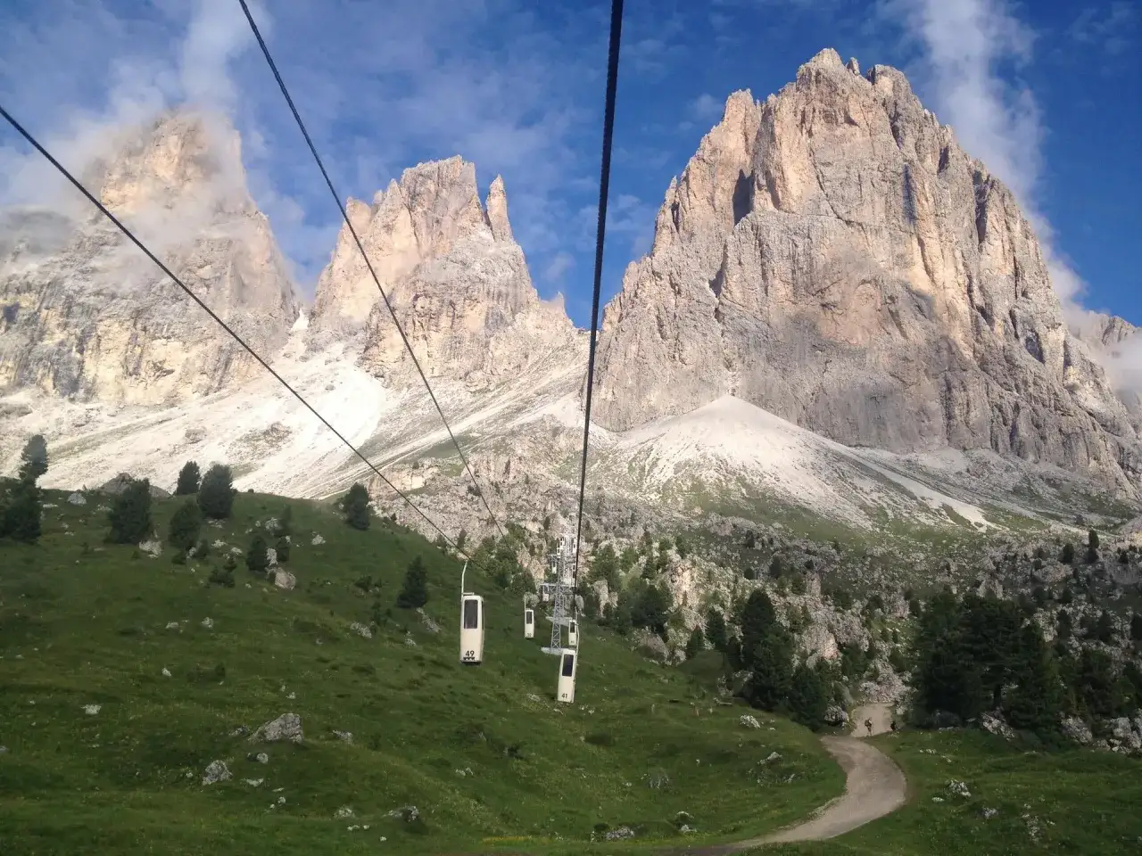 Kolejka linowa wjeżdża na Passo Giau, mijając zielone zbocza i skaliste szczyty Dolomit&oacute;w.