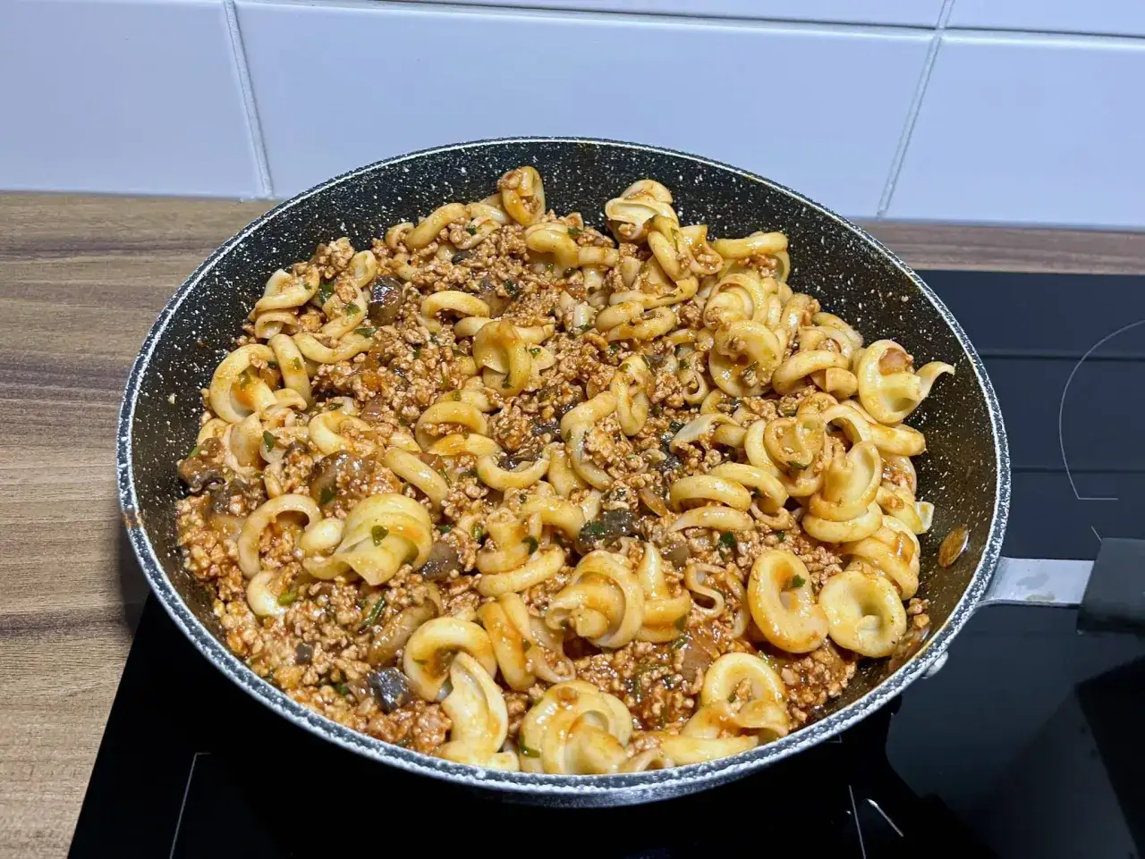 Pyszny makaron z mięsem wieprzowym i grzybami w sosie, gotowy do podania prosto z patelni.