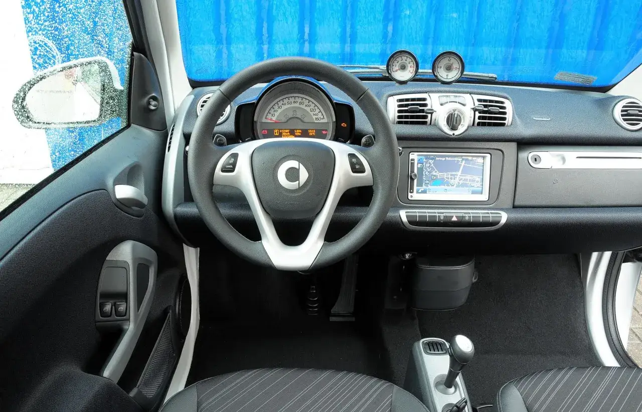 Wnętrze smart fortwo 450 z kierownicą, nawigacją i dwoma dodatkowymi zegarami.