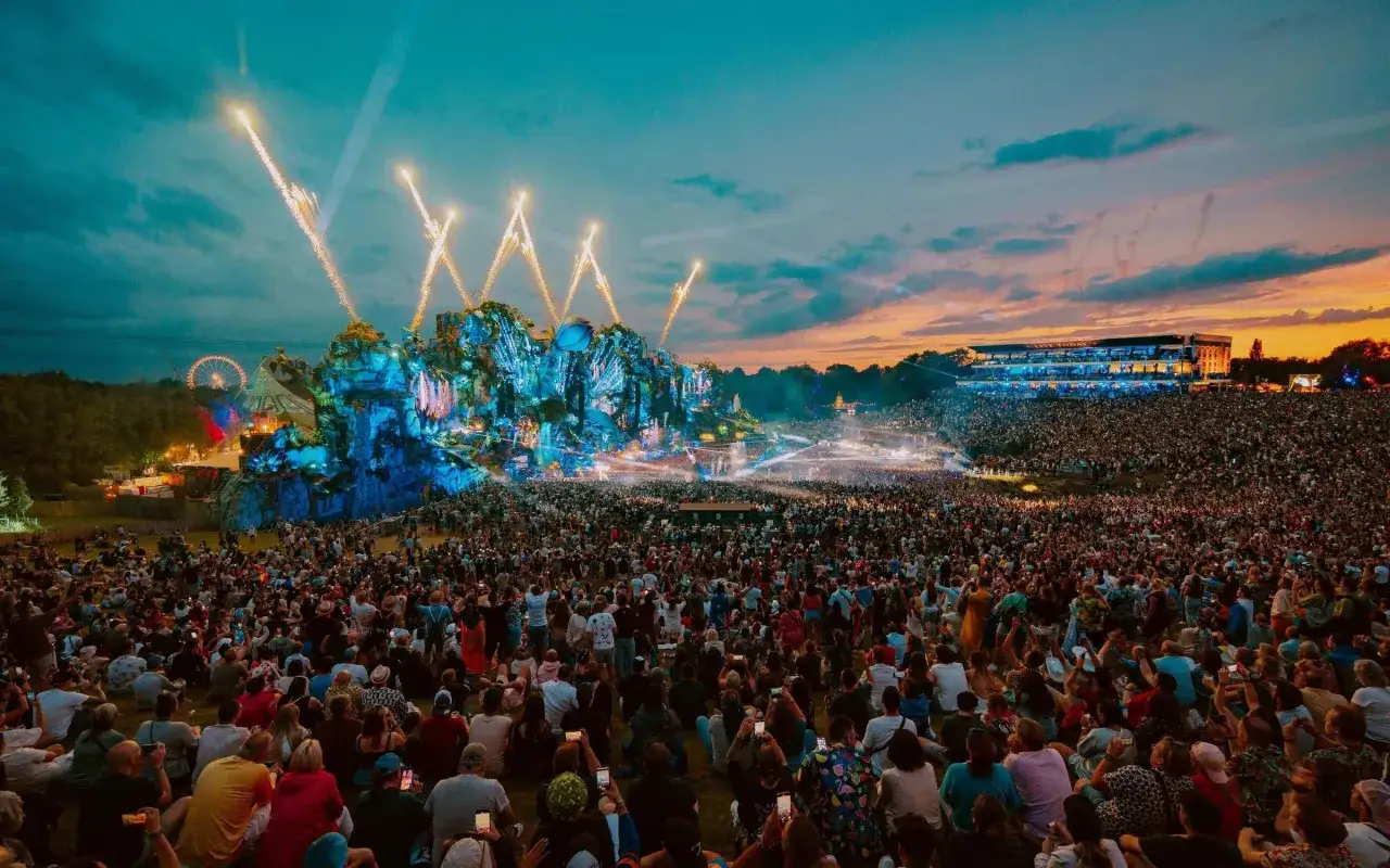 Un immenso pubblico assiste a uno spettacolo pirotecnico durante uno dei rave party pi&ugrave; famosi al mondo, con un palco elaborato e luci abbaglianti.