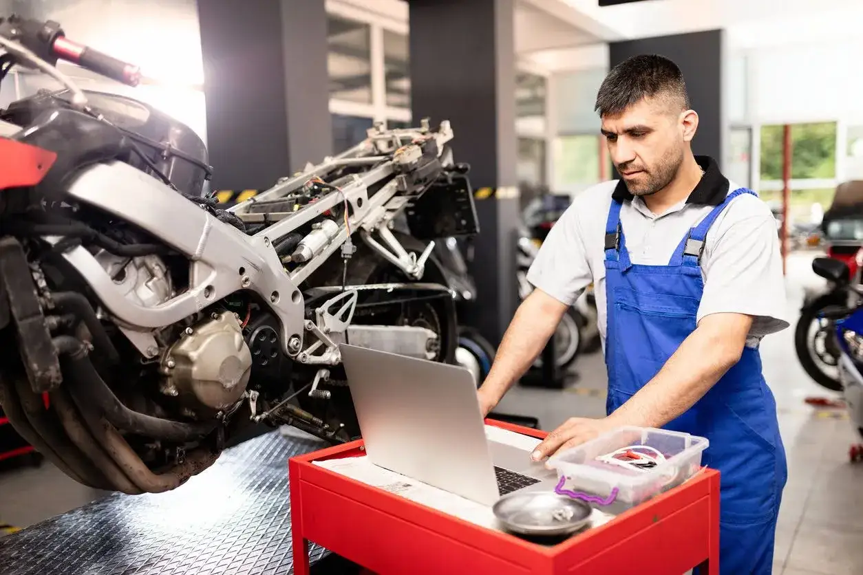 Mecánico revisa una moto que no enciende, usando una laptop para diagnosticar el problema.