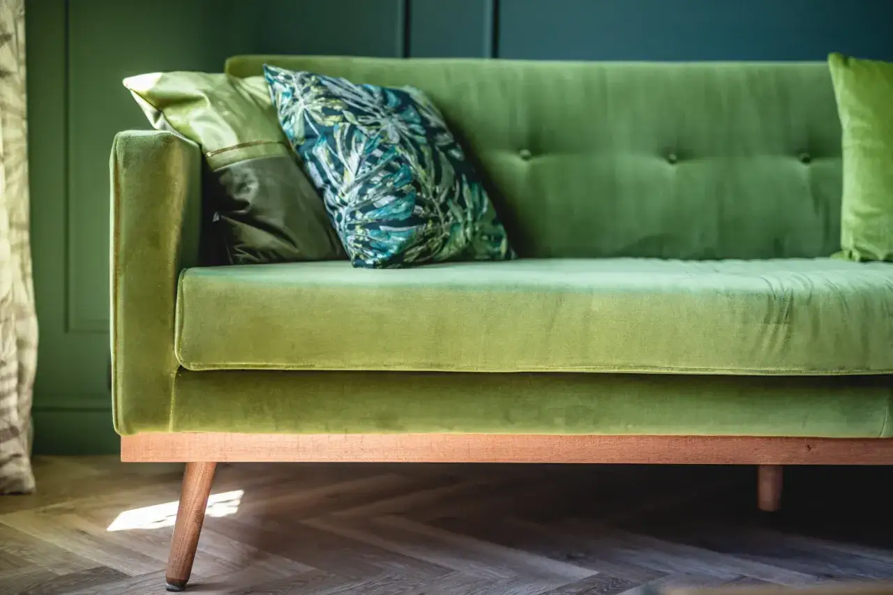Un canapé vert velours avec des coussins aux motifs tropicaux. Quelle couleur de rideaux irait avec ce canapé ?