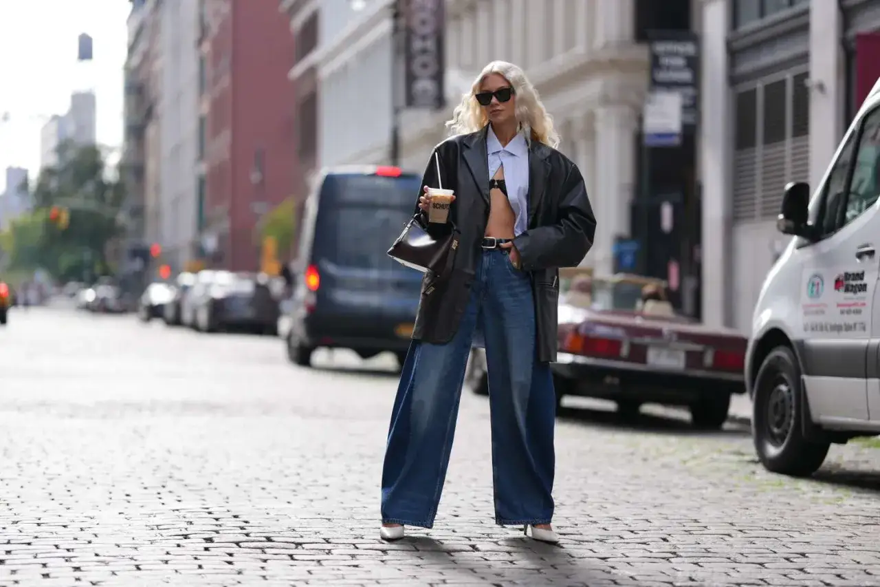 Modna kobieta w szerokich jeansach i skórzanej marynarce, prezentująca stylowe stylizacje z jeansami na ulicy.