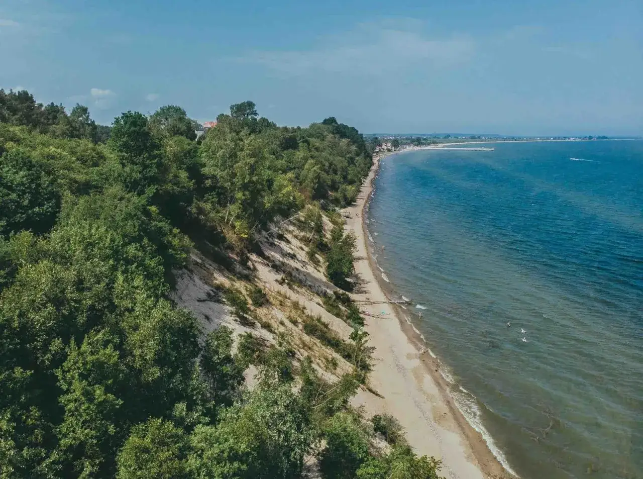Mechelinki atrakcje: piaszczysta plaża, klif porośnięty drzewami i turkusowe morze. Idealne miejsce na letni wypoczynek.