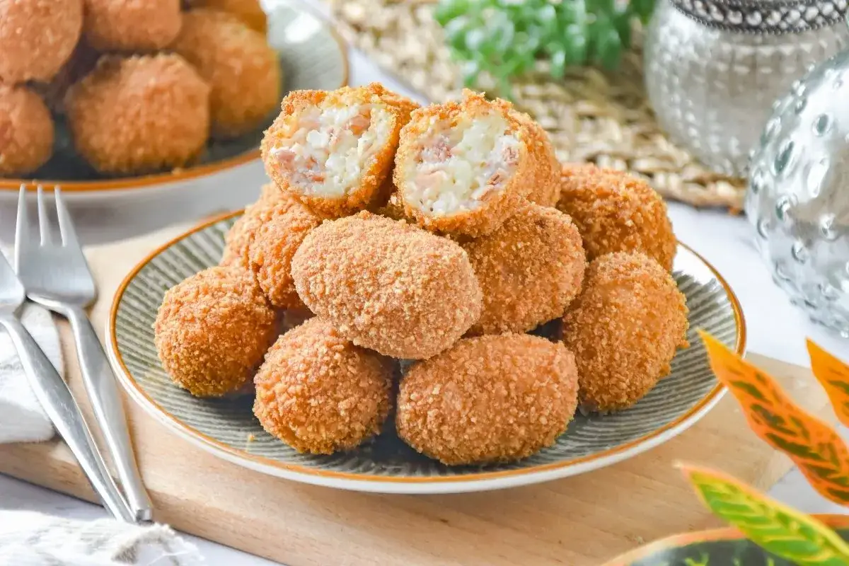 Una pila de croquetas de jam&oacute;n doradas y crujientes, una partida por la mitad revela un interior cremoso.