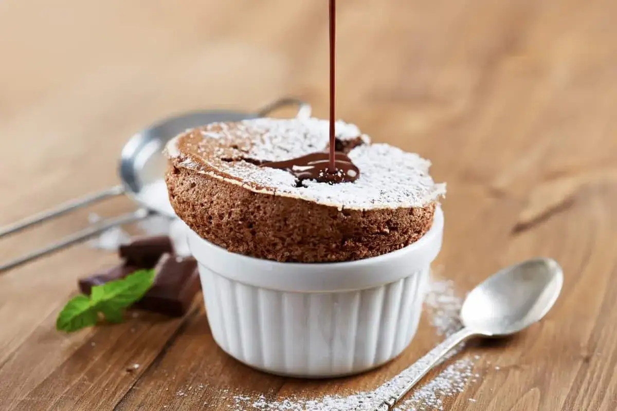 Delicioso soufflé de chocolate cubierto de azúcar glas, con sirope de chocolate cayendo.