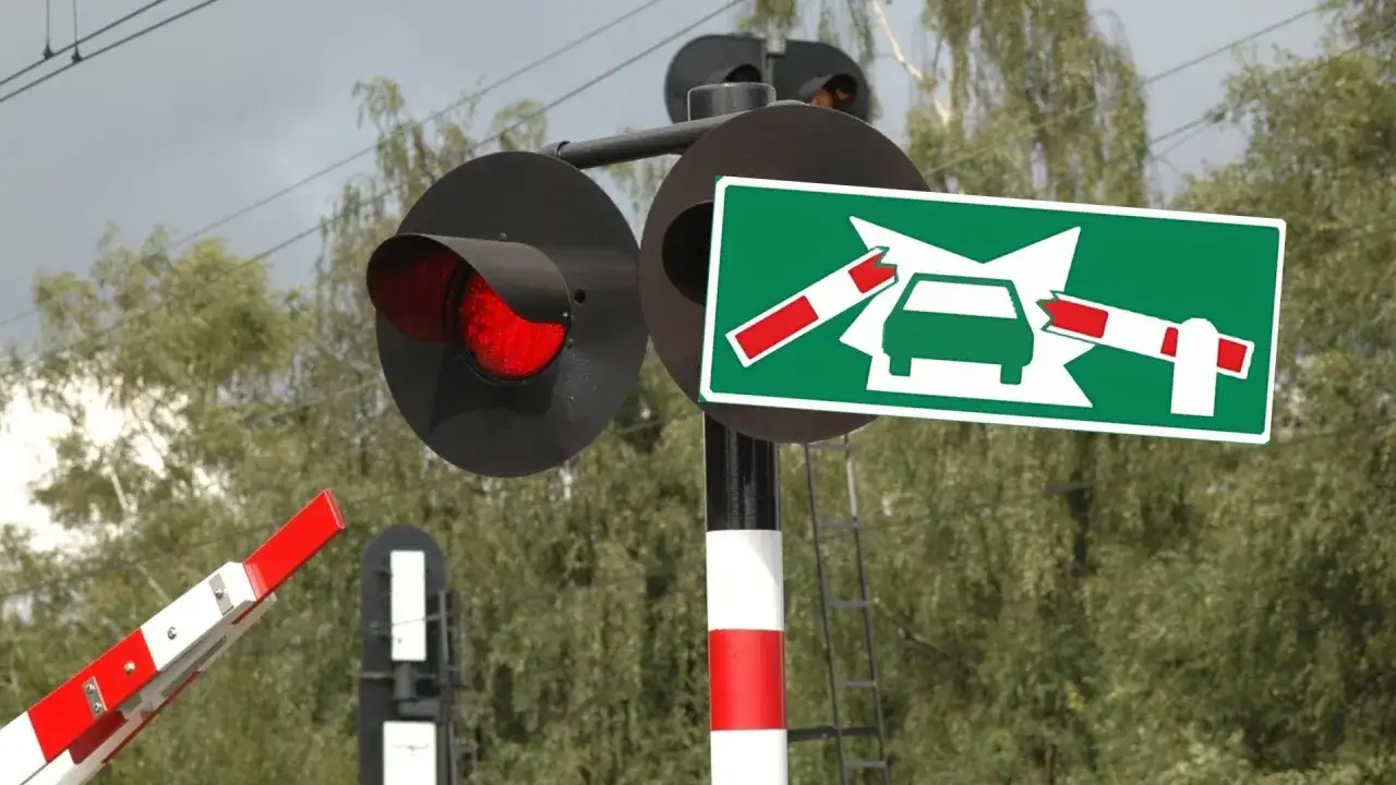 Czerwone światło na przejeździe kolejowo-drogowym. Znak ostrzega przed możliwością uderzenia w opuszczany szlaban.