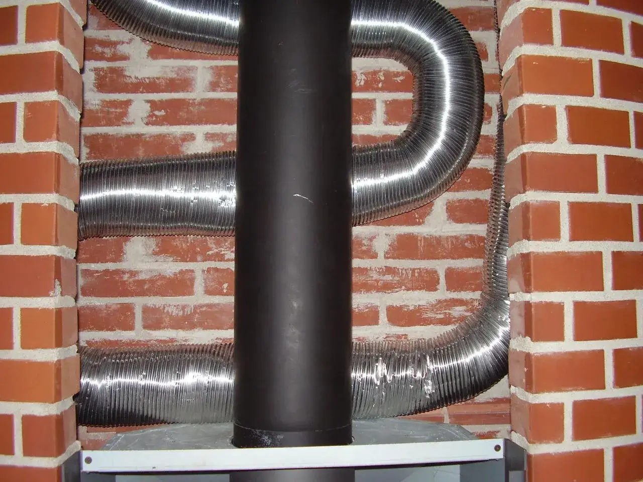 Mur brique r&eacute;fractaire derri&egrave;re po&ecirc;le, avec gaines argent&eacute;es. Installation de conduit de fum&eacute;e.