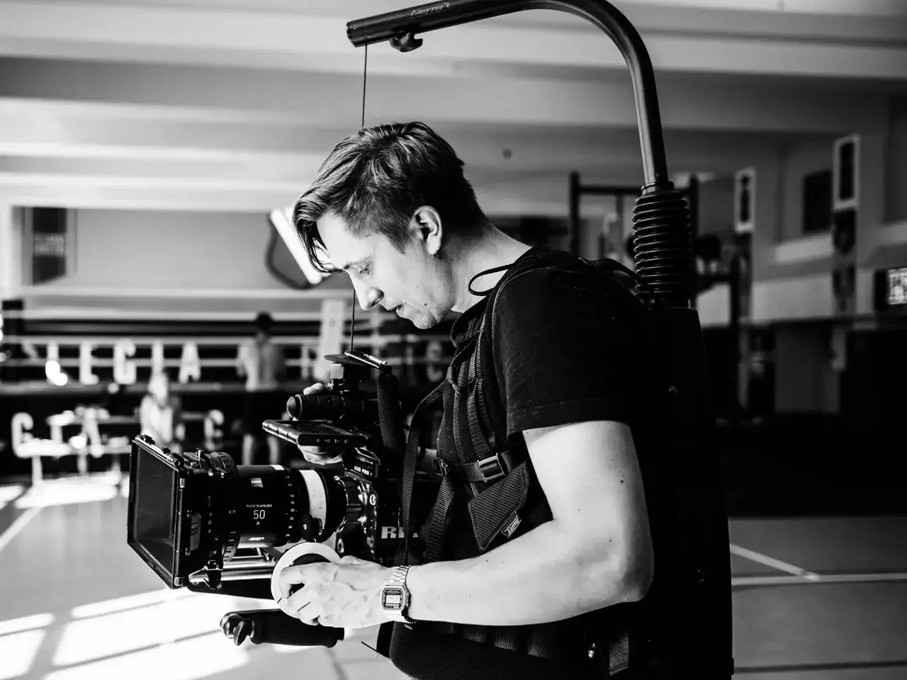Mikołaj Syguda w akcji, z kamerą na stabilizatorze. Skupiony operator tworzy filmowe ujęcia.