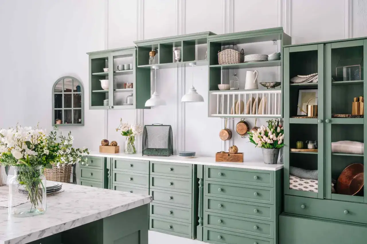Cucina in stile provenzale casa con mobili verdi, stoviglie, pentole in rame e fiori freschi.