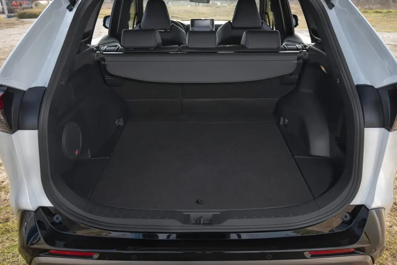 Pusta przestrzeń bagażowa w białym Toyota RAV4 2020, gotowa na podróż. Widoczne tylne siedzenia i subwoofer.