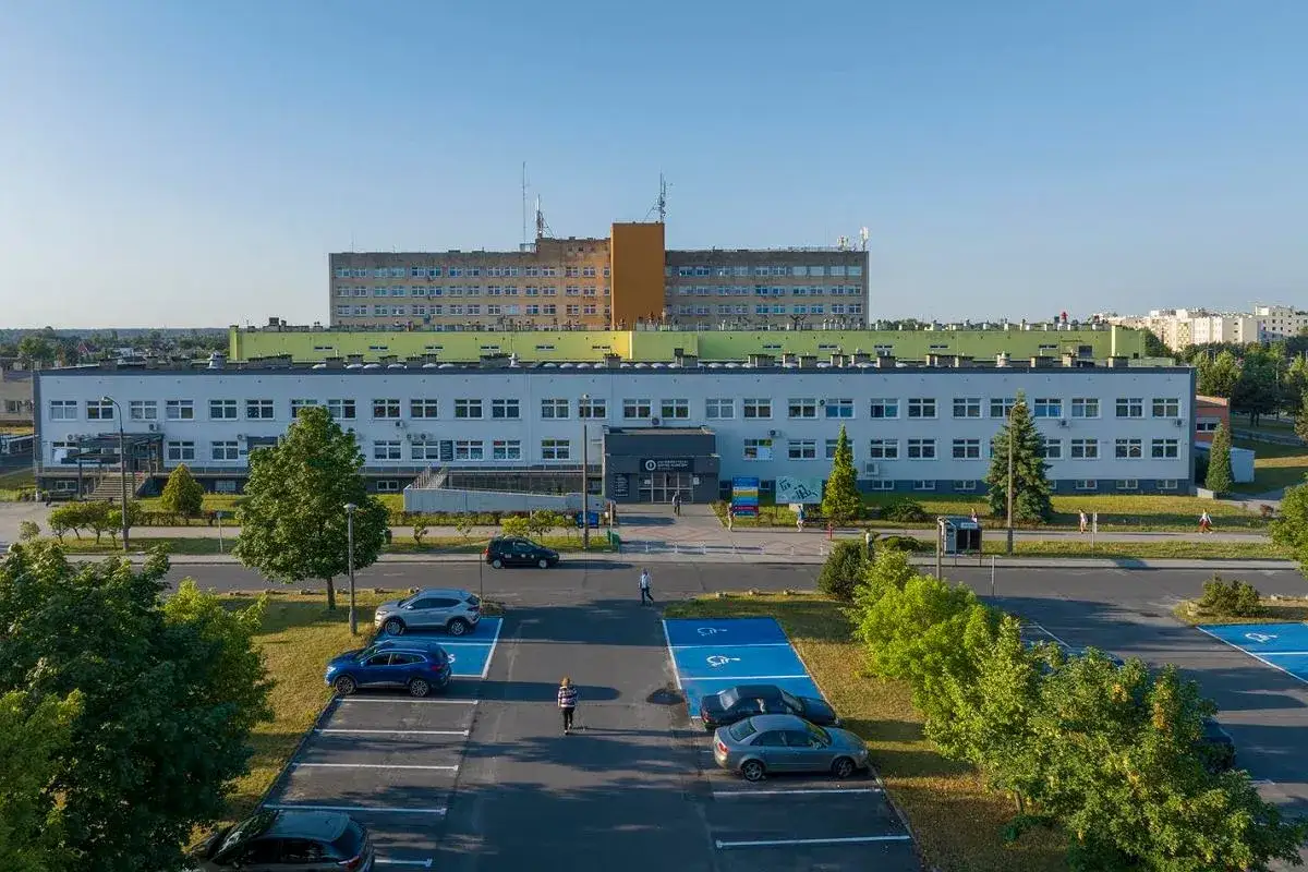 Budynek szpitala z parkingiem i zielenią w Opolu.