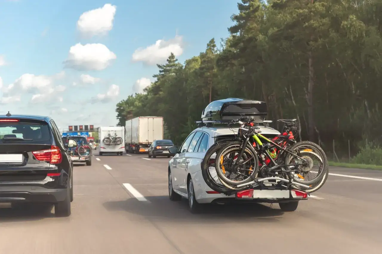 Biały kombi z bagażnikiem dachowym i rowerami z tyłu jedzie autostradą. Sprawdzono dopuszczalne obciążenie dachu.