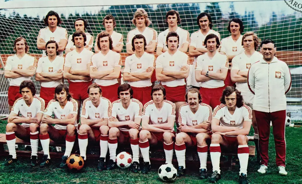 Reprezentacja Polski 1974 skład: piłkarze w białych koszulkach z orzełkiem i czerwonych spodenkach pozują do zdjęcia przed bramką.