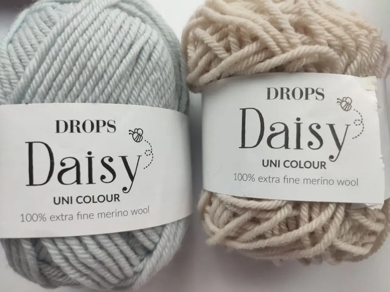 Dwa motki wł&oacute;czki Drops Daisy z wełny merino. Jeden jasnoszary, drugi beżowy.