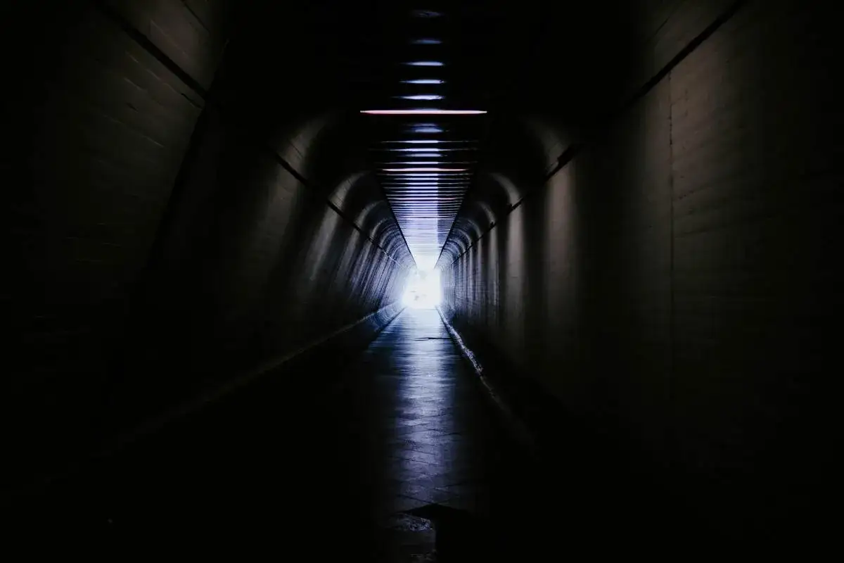 Oscuro t&uacute;nel con luz al final, evocando experiencias cercanas a la muerte.