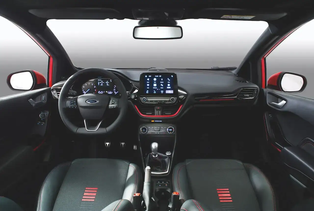 Interior del Ford Fiesta ST Line: volante deportivo, pantalla táctil central y asientos con detalles rojos.