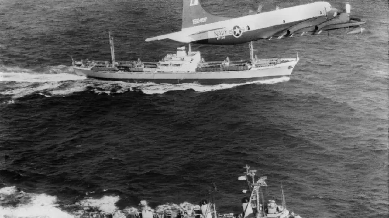 Ein US-Aufklärungsflugzeug überfliegt ein Schiff während der Operation Anadyr. Ein weiteres Schiff ist im Vordergrund zu sehen.