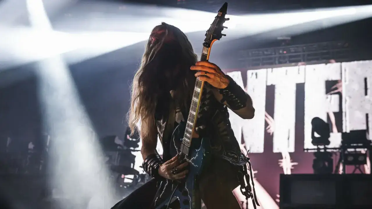 Pantera w Polsce: gitarzysta z długimi włosami gra na scenie, w tle logo zespołu.
