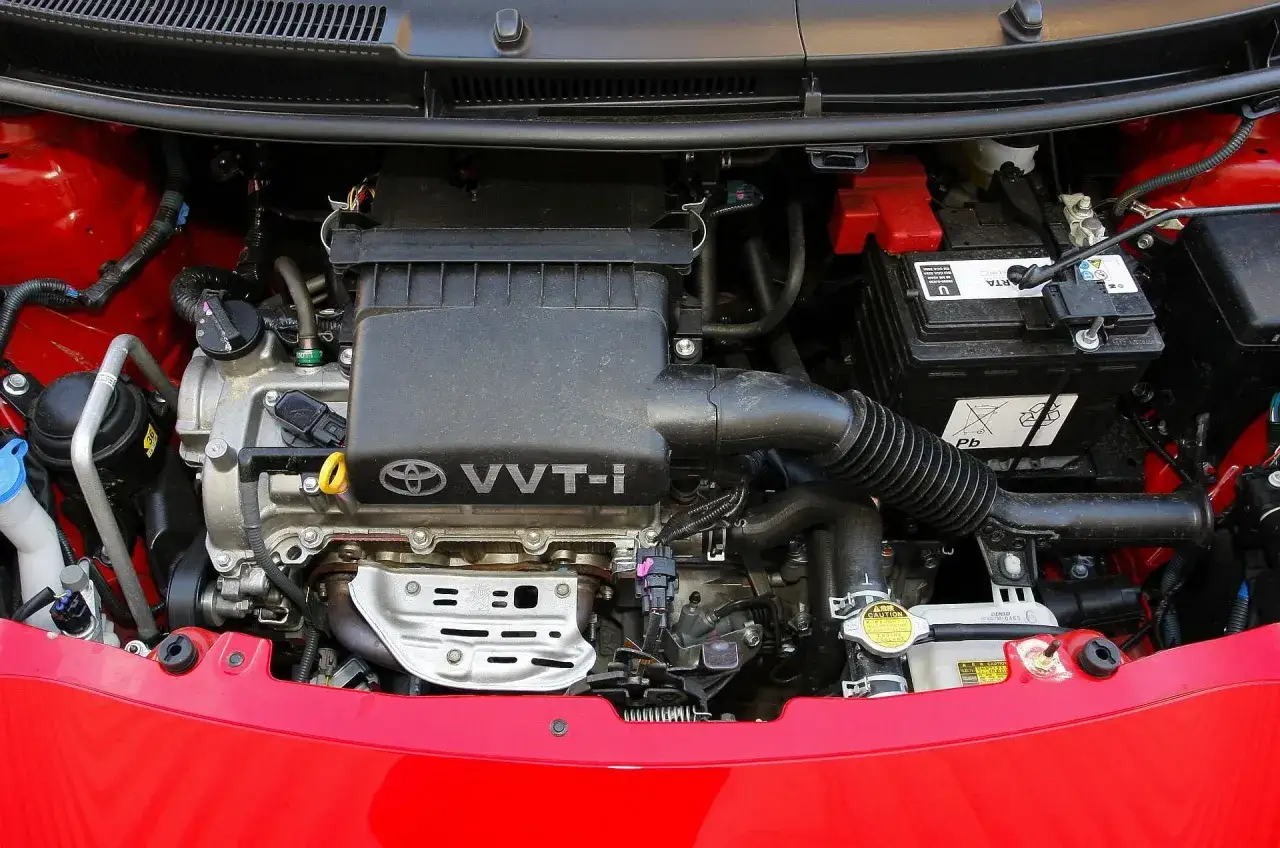 Silnik VVT-i w Toyocie Yaris 2. Widoczny akumulator, przewody i elementy układu dolotowego.