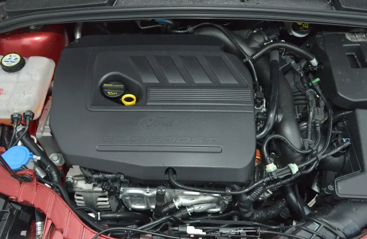 Silnik 1.0 EcoBoost w samochodzie Ford. Widoczna czarna pokrywa silnika z napisem 