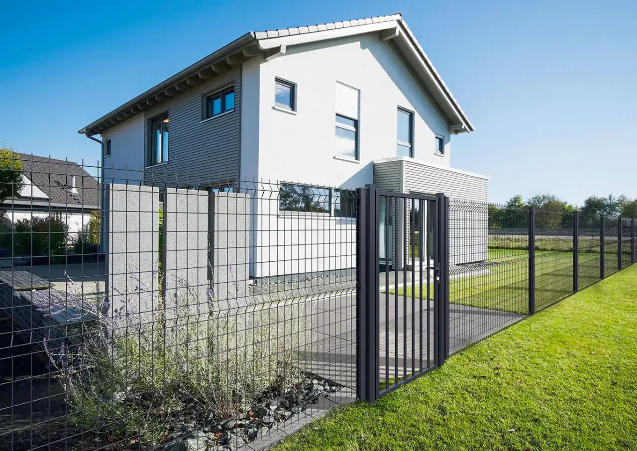 Maison moderne avec portail et pose grillage rigide, d&eacute;limitant un jardin verdoyant.