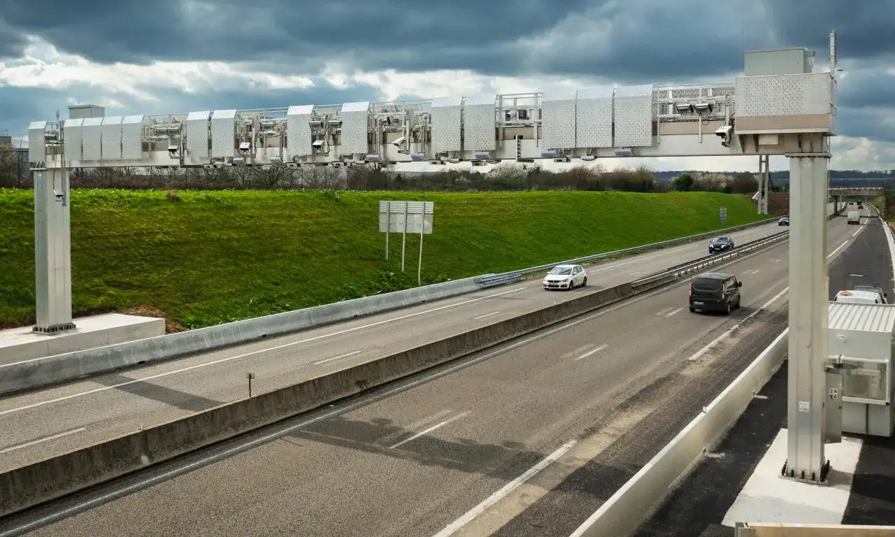 Portique de péage automatique sur une autoroute en France. Des voitures circulent sous la structure métallique équipée de caméras.