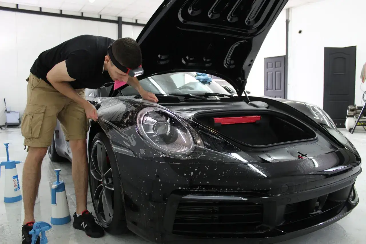 Profesjonalne oklejanie folią PPF czarnego Porsche. Detailing auta w warsztacie.