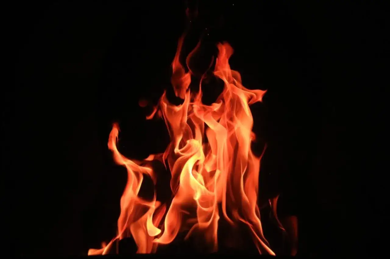Vibrant orange flames dance against a black background, a captivating example of fire photography.