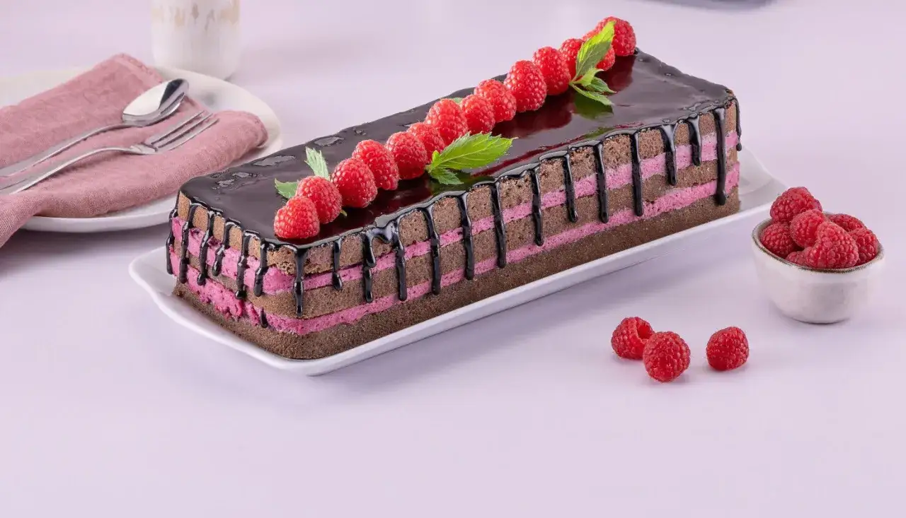 Schoko Himbeer Torte mit glänzendem Schokoladenguss, Himbeeren und Minze verziert.