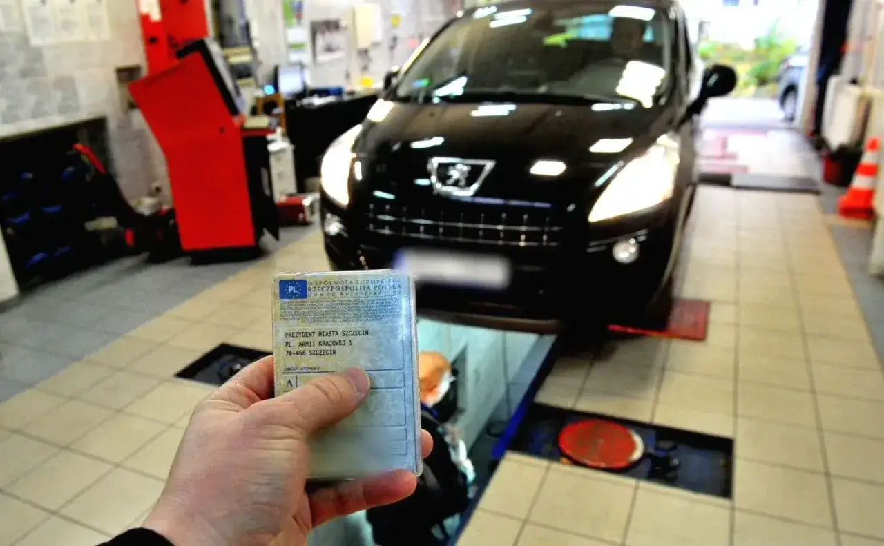 Czarny Peugeot, jeden z wielu sportowych hatchbacków, w warsztacie. W ręce trzymany dowód rejestracyjny.
